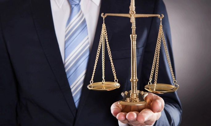 A person in a suit holds a balance scale.