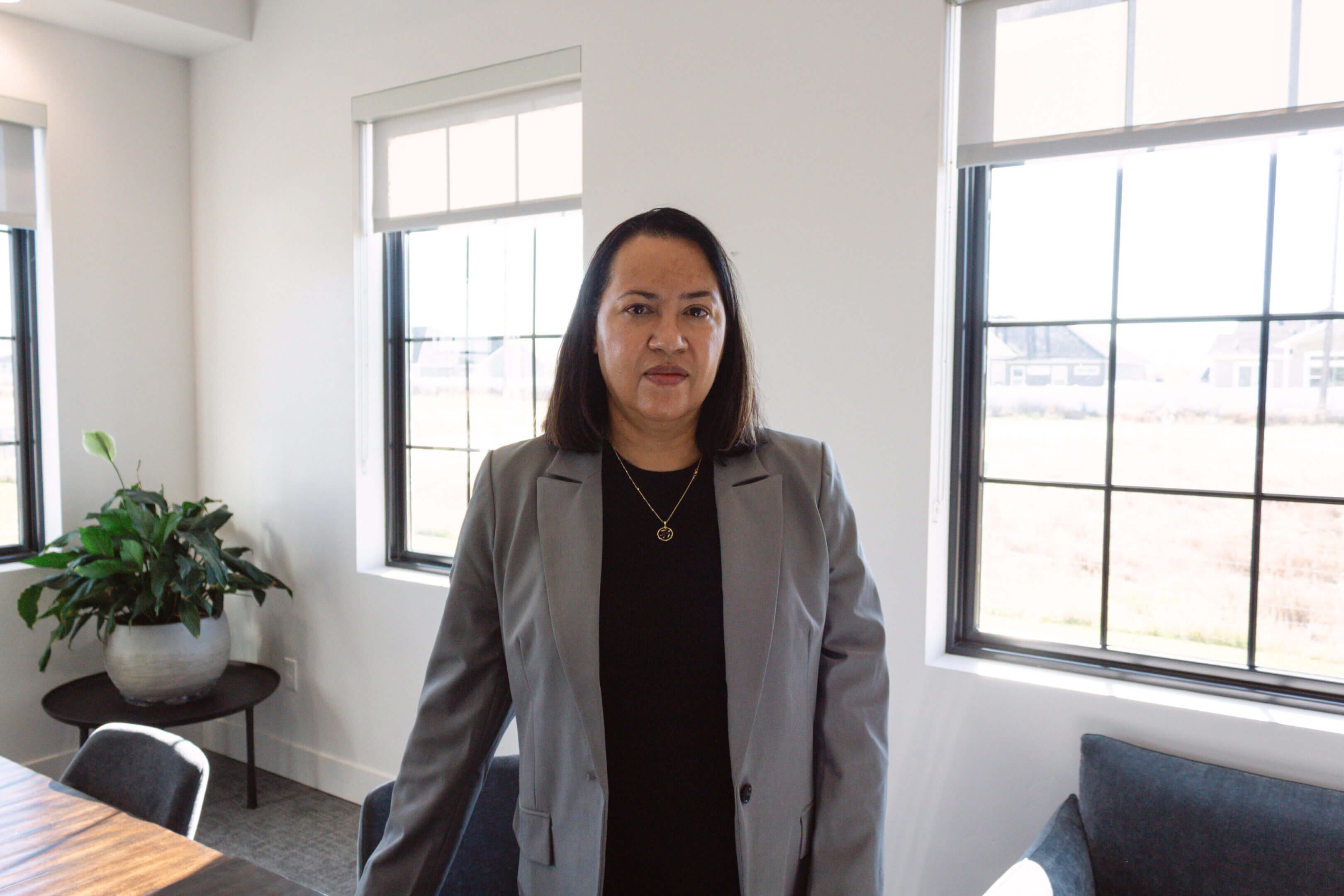 Person in gray suit in office setting.